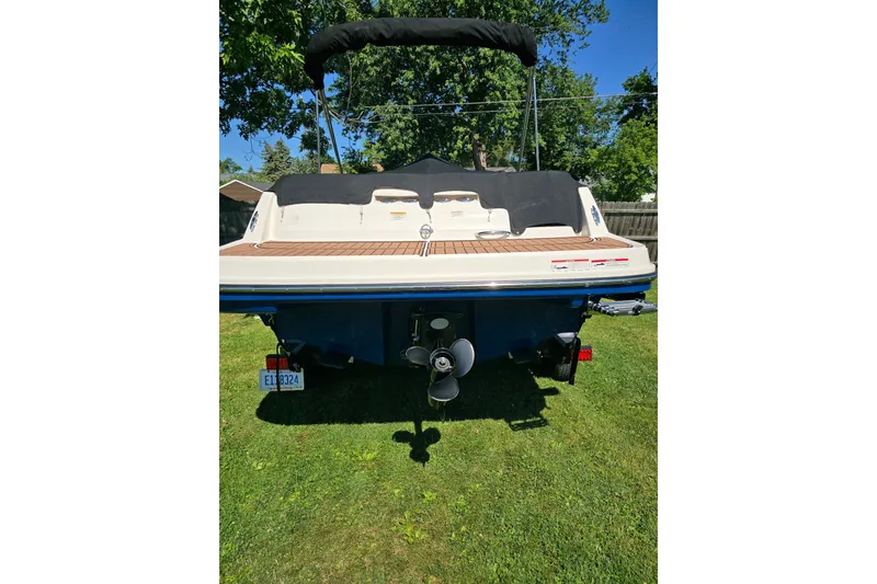 Slide: The Image of 2019 Bayliner VR6 Bowrider I/O boat, rear view on grass, with canopy and propeller visible. - 10