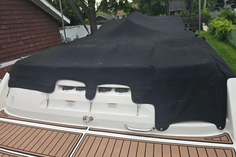 Slide: The Image of 2019 Bayliner VR6 Bowrider I/O covered, rear view with black tarp and wooden deck. - 19