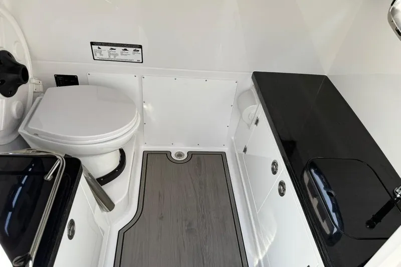 Slide: The Image of 2026 Monterey Elite 27 SD boat bathroom with toilet, black countertop, and wood-style flooring. - 13