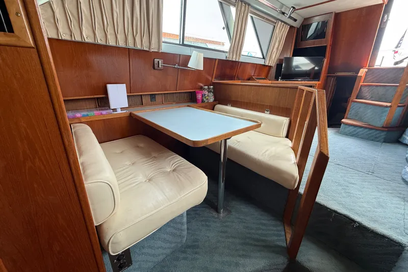 Slide: The Image of 1987 Sea Ray 410 Aft Cabin interior with dining area, wood paneling, and seating. - 20