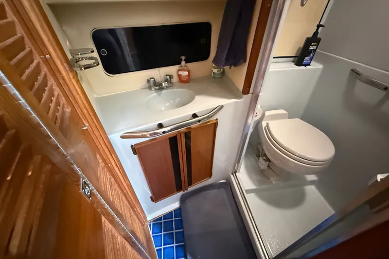 Slide: The Image of 1987 Sea Ray 410 Aft Cabin bathroom with sink, toilet, and wooden cabinetry. - 26