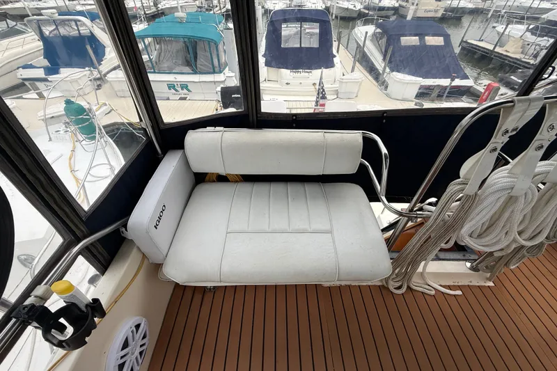 Slide: The Image of 1987 Sea Ray 410 Aft Cabin interior with white seating and marina view. - 53