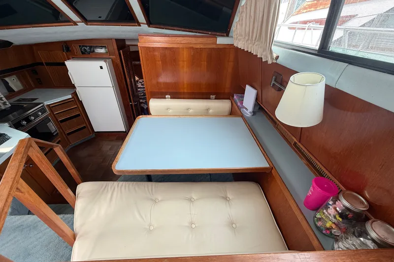 Slide: The Image of 1987 Sea Ray 410 Aft Cabin interior with dining area, kitchen, and wooden cabinetry. - 15