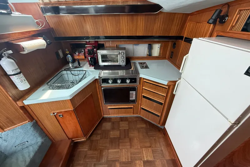 Slide: The Image of 1987 Sea Ray 410 Aft Cabin kitchen with wood cabinetry, appliances, and sink. - 16