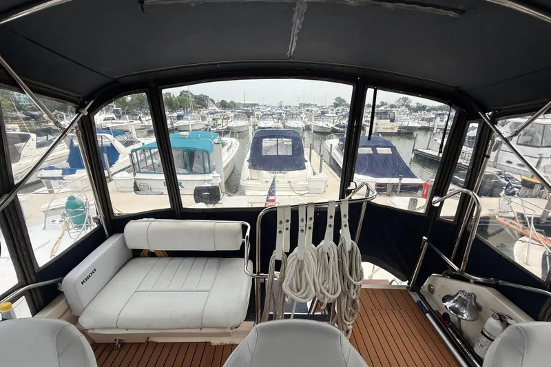 Slide: The Image of 1987 Sea Ray 410 Aft Cabin interior view at marina, showcasing seating and docked boats. - 54