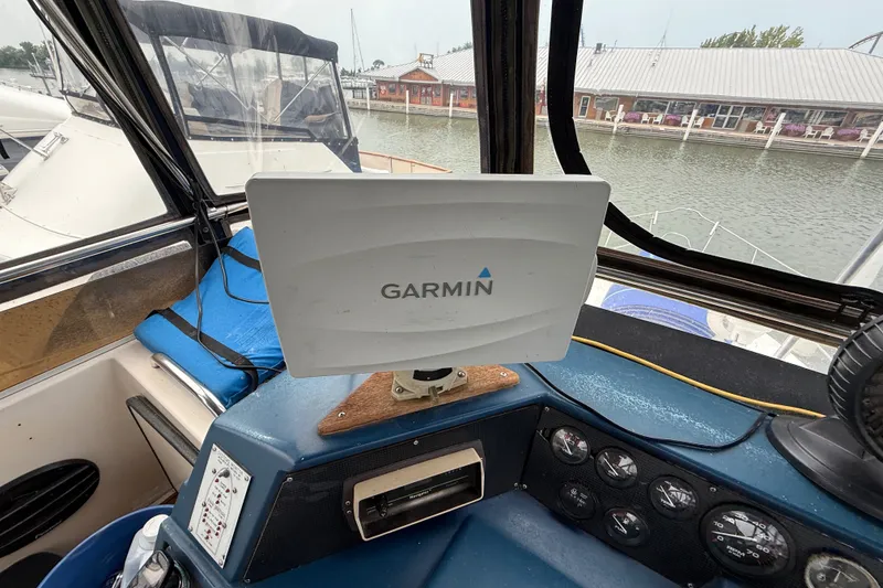 Slide: The Image of 1987 Sea Ray 410 Aft Cabin helm with Garmin navigation system, docked by waterfront buildings. - 43