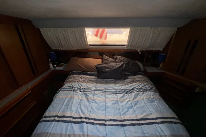 Slide: The Image of Cozy bedroom in 1987 Sea Ray 410 Aft Cabin yacht with striped bedding and window view. - 29