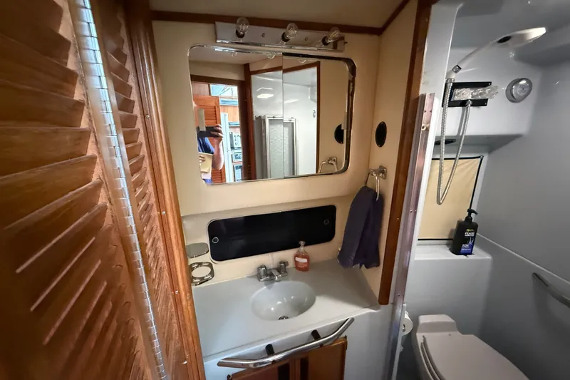 Slide: The Image of 1987 Sea Ray 410 Aft Cabin bathroom with sink, mirror, and shower. - 25