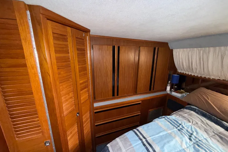 Slide: The Image of 1987 Sea Ray 410 Aft Cabin interior with wooden cabinets and cozy bedding. - 30