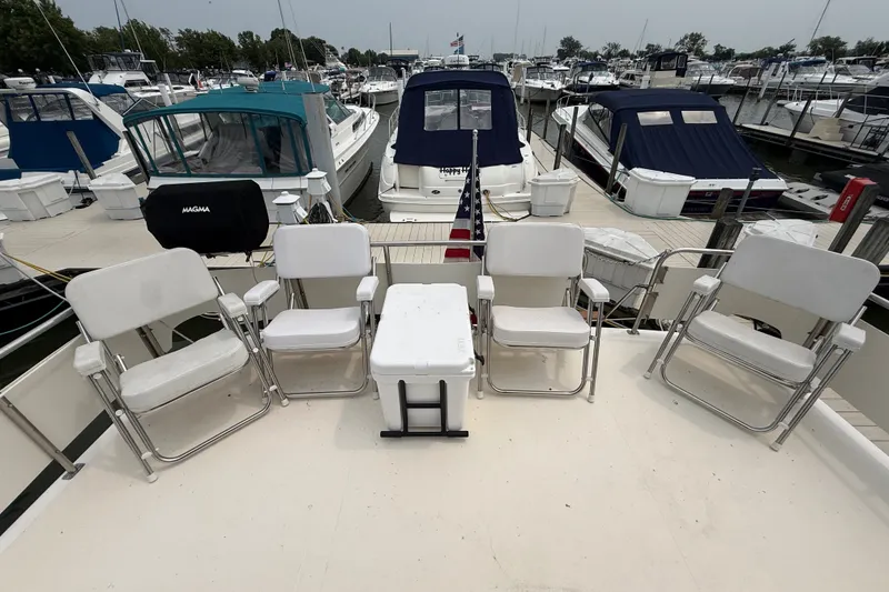 Slide: The Image of 1987 Sea Ray 410 Aft Cabin yacht deck with chairs and cooler at marina. - 7