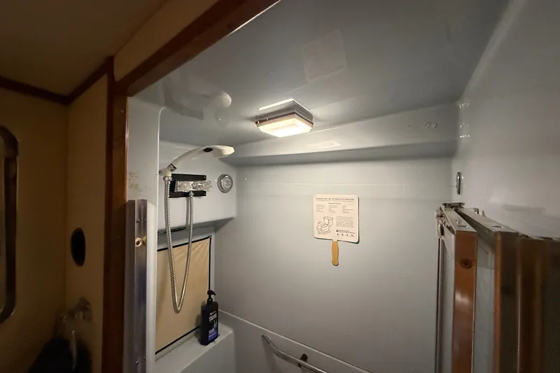 Slide: The Image of Shower area inside 1987 Sea Ray 410 Aft Cabin yacht, featuring a modern showerhead and lighting. - 27