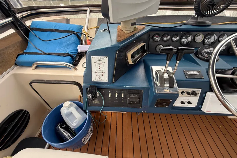 Slide: The Image of 1987 Sea Ray 410 Aft Cabin helm with controls, gauges, and wooden flooring. - 49