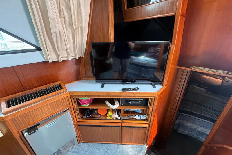 Slide: The Image of Interior of 1987 Sea Ray 410 Aft Cabin with TV, shelves, and mini-fridge. - 14