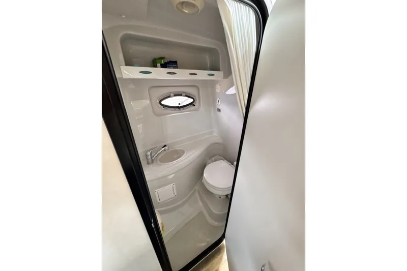 Slide: The Image of Compact bathroom in 2010 Crownline 280 CRX boat with sink, toilet, and porthole window. - 15