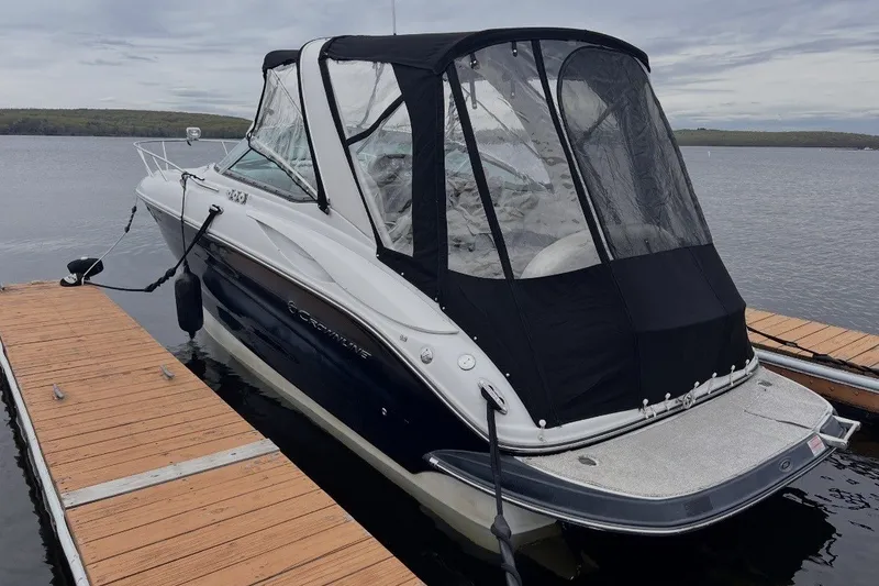 The Image of 2010 Crownline 280 CRX boat docked on calm water with black canopy. - 1