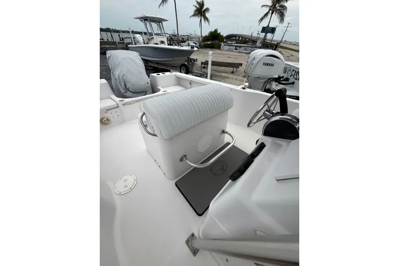 Slide: The Image of 2003 Pro-Line 22 Sport boat interior with steering wheel and seating, docked near palm trees. - 14