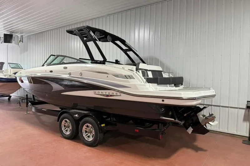 Slide: The Image of 2025 Monterey M6 boat in showroom, sleek design, black and white exterior, on trailer. - 1