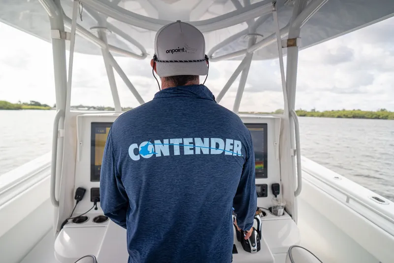 Slide: The Image of Person steering a 2023 Contender 44 ST boat, wearing a branded shirt and cap. - 34