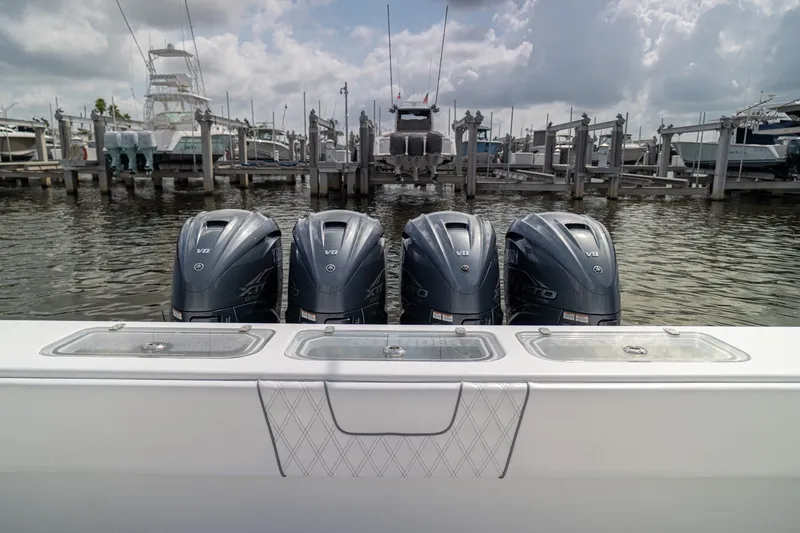 Slide: The Image of Four powerful outboard motors on a 2023 Contender 44 ST boat docked at a marina. - 14