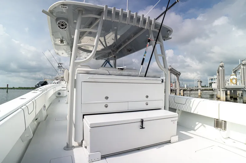 Slide: The Image of 2023 Contender 44 ST boat interior with storage, fishing rods, and seating under a cloudy sky. - 17