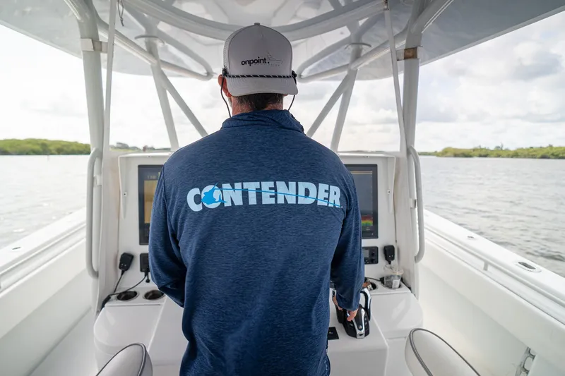 Slide: The Image of Person steering a 2023 Contender 44 ST boat, wearing branded jacket and cap. - 35