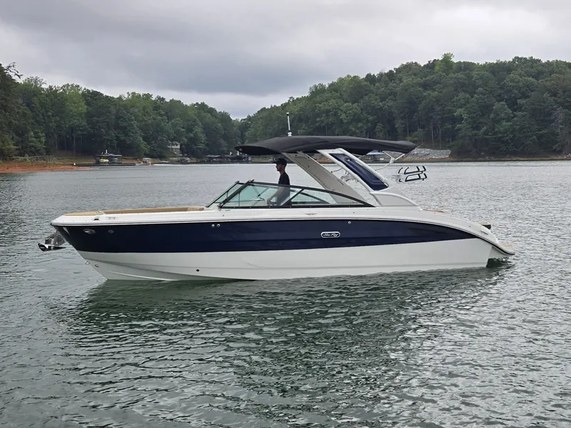 Slide: The Image of A 2027 Sea Ray SDX 270 Surf on a calm lake, surrounded by wooded hills. - 0