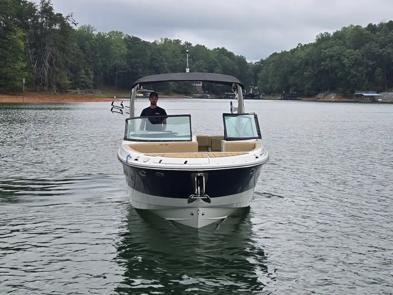 Slide: The Image of A 2027 Sea Ray SDX 270 Surf on a calm lake with wooded shores. - 2
