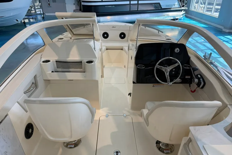 Slide: The Image of 2026 Scout 240 Dorado boat interior with modern helm and seating in showroom. - 16