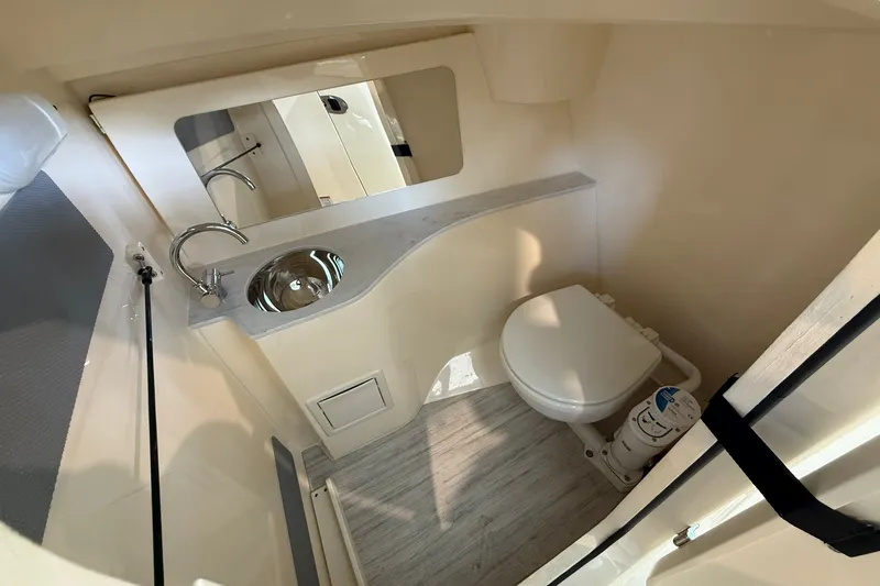 Slide: The Image of 2026 Scout 240 Dorado boat interior with compact bathroom, featuring sink and toilet. - 8