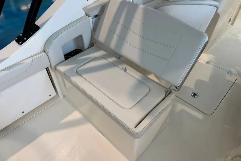 Slide: The Image of 2026 Scout 240 Dorado boat interior with white cushioned seating and storage compartment. - 13