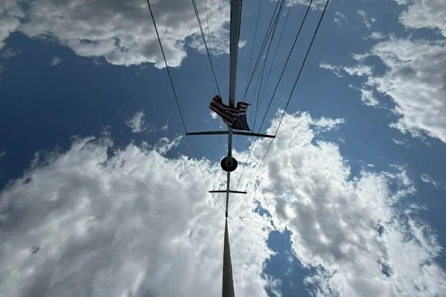 Slide: The Image of View of Catalina 400 sailboat mast against cloudy sky, featuring an American flag. - 13