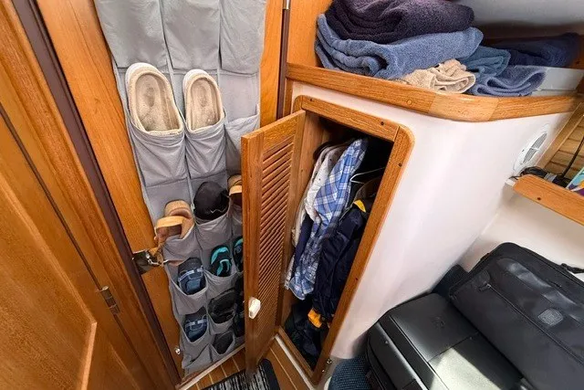 Slide: The Image of Storage area inside a 2005 Catalina 400 sailboat, featuring organized shoes and clothing. - 49
