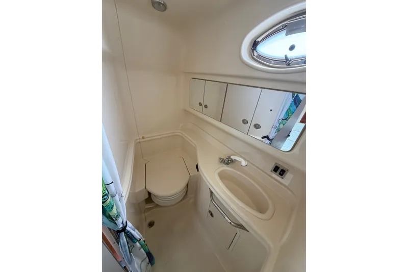 Slide: The Image of Bathroom interior of 2005 Sea Ray 340 Sundancer yacht, featuring sink, toilet, and porthole window. - 10
