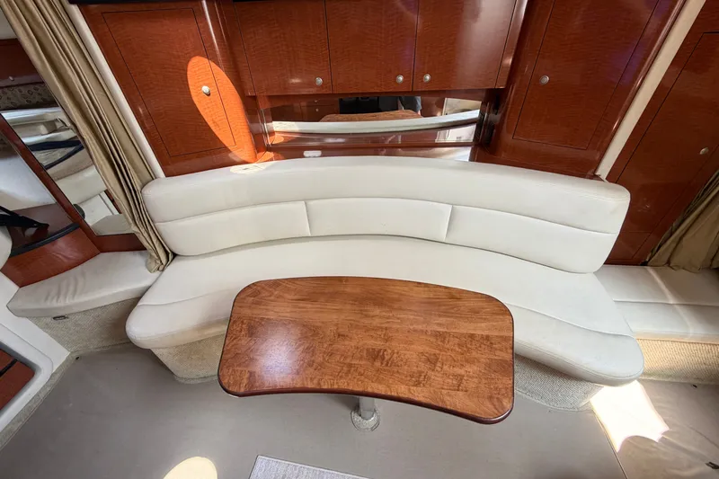 Slide: The Image of Interior of 2005 Sea Ray 340 Sundancer with curved seating and wooden table. - 12