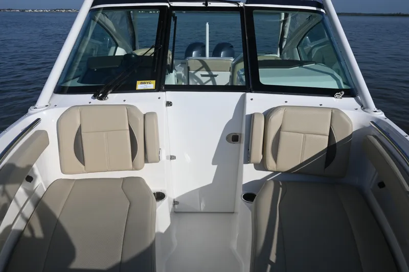 Slide: The Image of 2021 Pursuit DC 266 Dual Console boat interior with beige seating on calm water. - 15