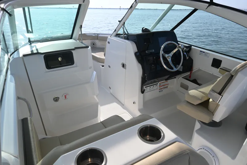 Slide: The Image of 2021 Pursuit DC 266 Dual Console boat interior with steering wheel and seating, on calm water. - 19