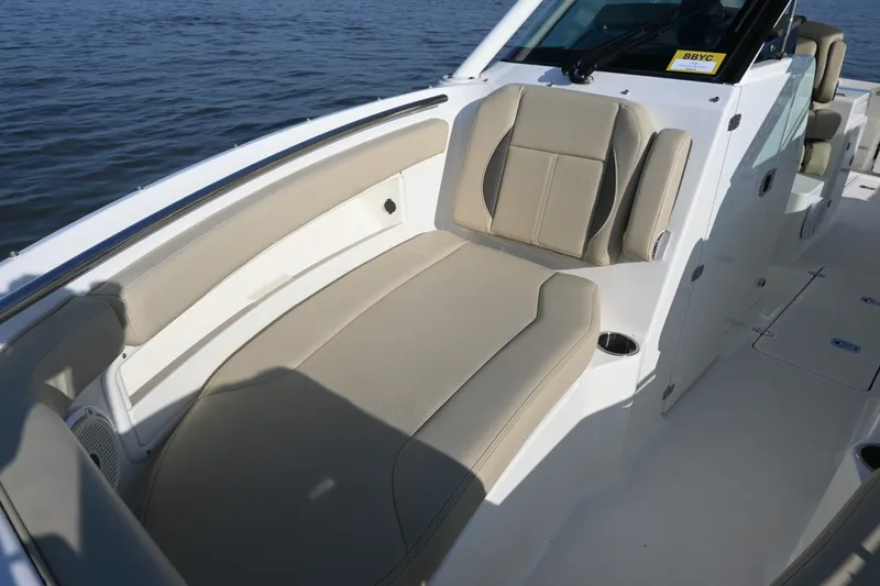 Slide: The Image of 2021 Pursuit DC 266 Dual Console boat interior with beige seating, on calm water. - 16