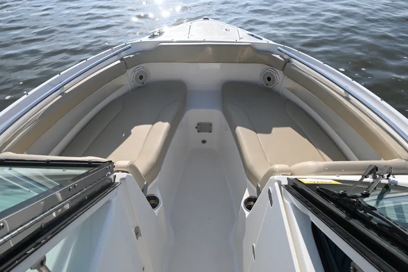 Slide: The Image of 2021 Pursuit DC 266 Dual Console boat interior with beige seating on calm water. - 13