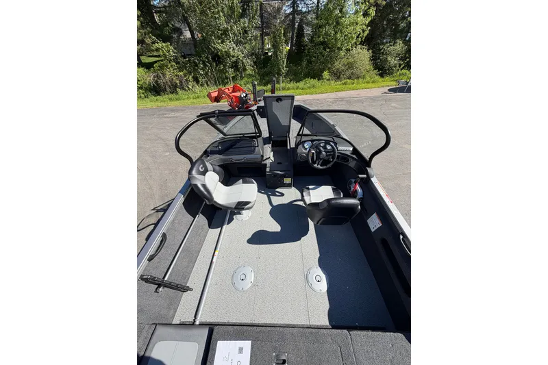 Slide: The Image of 2026 Crestliner 1750 Hawk WT boat interior with seating and steering wheel, parked outdoors. - 22