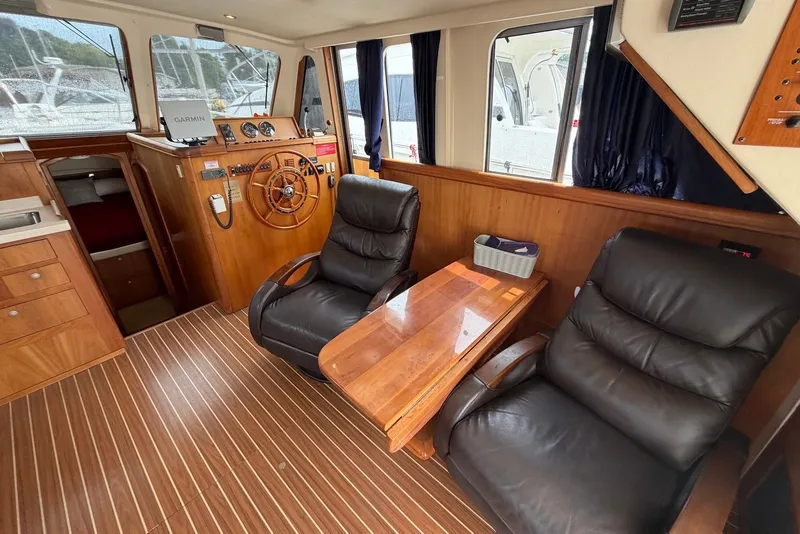 Slide: The Image of 2004 Mainship 390 Trawler interior with leather chairs, wooden helm, and navigation equipment. - 14