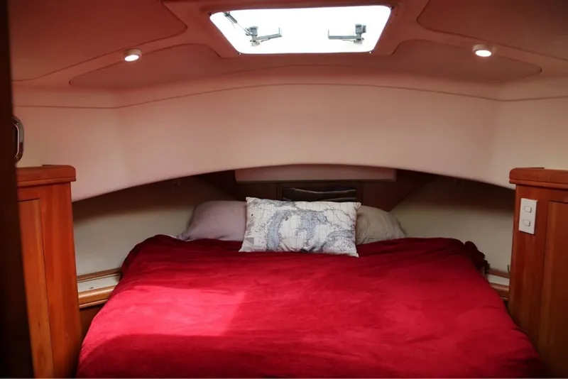 Slide: The Image of Cozy cabin interior of 2004 Mainship 390 Trawler with red bedding and skylight. - 20