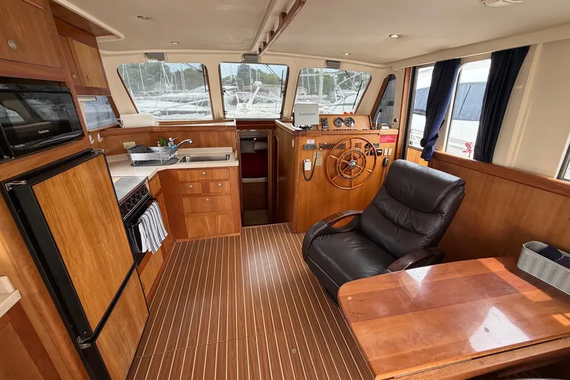 Slide: The Image of 2004 Mainship 390 Trawler interior with wood finish, helm, and kitchenette. - 15