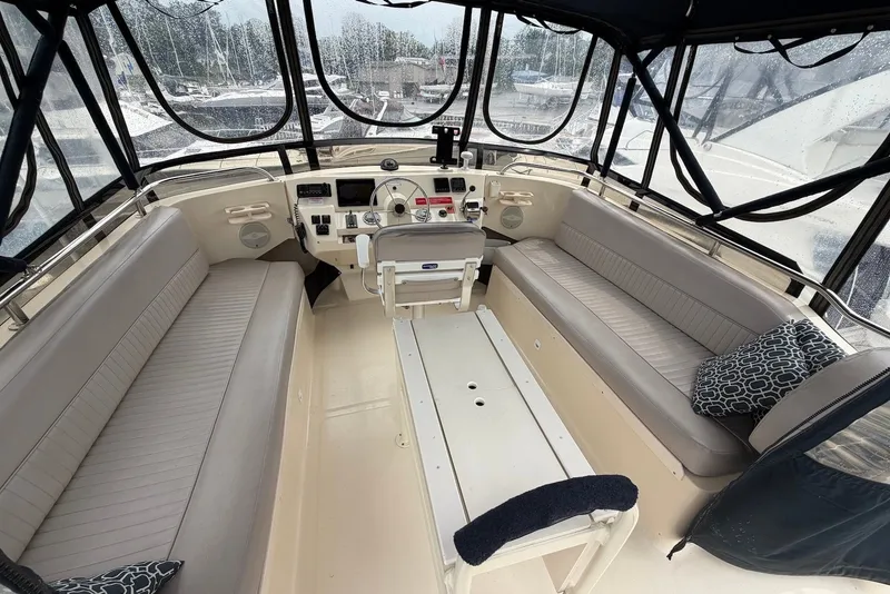 Slide: The Image of 2004 Mainship 390 Trawler helm with seating, steering wheel, and navigation controls. - 4