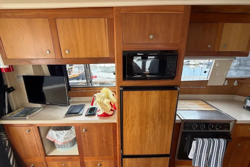 Slide: The Image of Interior of a 2004 Mainship 390 Trawler with wooden cabinets, microwave, and TV. - 18