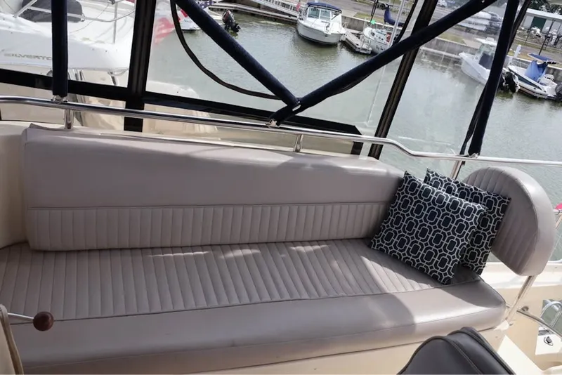Slide: The Image of 2004 Mainship 390 Trawler interior with cushioned seating and decorative pillow, docked at marina. - 7