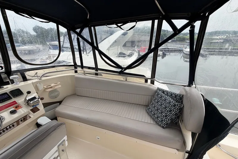 Slide: The Image of 2004 Mainship 390 Trawler interior with helm, seating, and marina view. - 6
