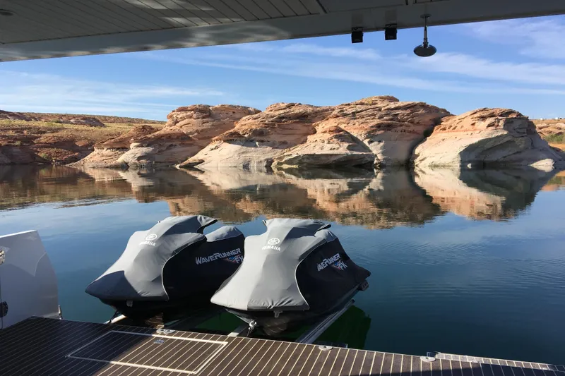 Slide: The Image of Jet skis on a boat deck with rocky landscape reflection on calm water. - 43