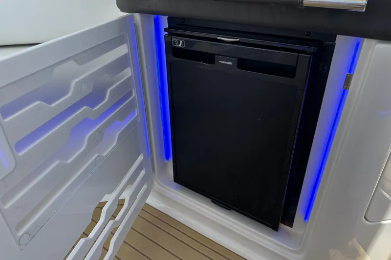 Slide: The Image of 2018 Sea Ray SLX 310 Outboard interior with built-in Dometic refrigerator and blue LED lighting. - 9