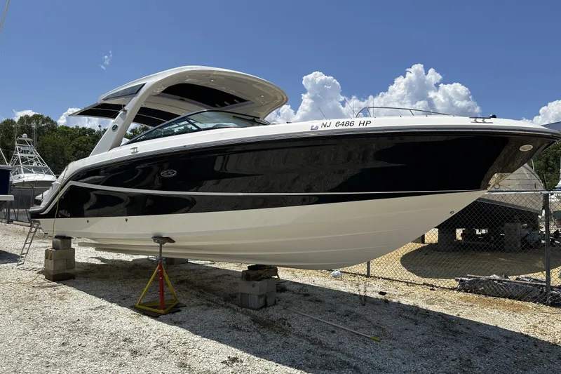 Slide: The Image of 2018 Sea Ray SLX 310 Outboard boat on dry dock under a clear blue sky. - 5