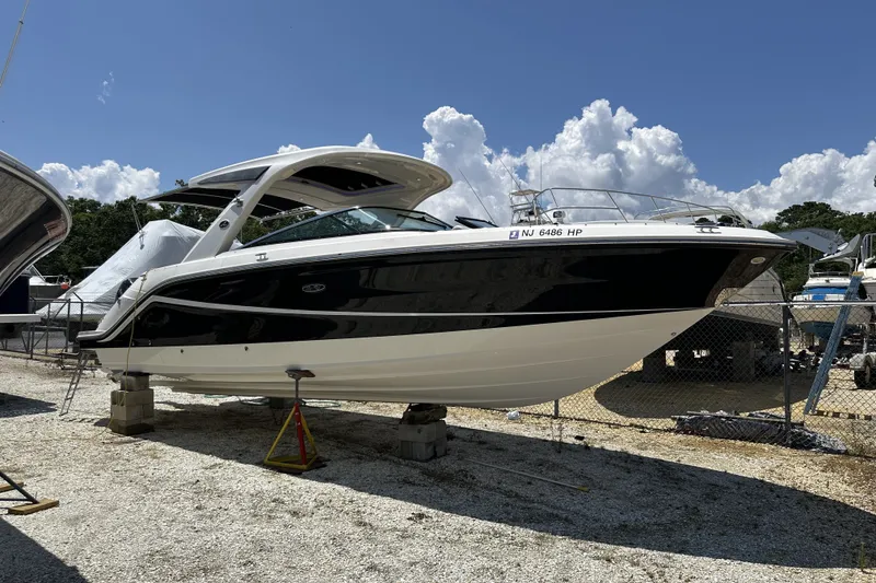 Slide: The Image of 2018 Sea Ray SLX 310 Outboard boat on dry dock under a clear blue sky. - 40